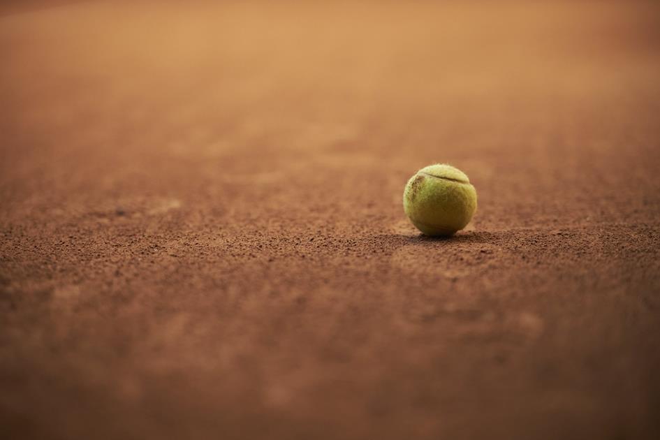 green-tennis-ball-brown-tennis-court-background-yellow-tennis-ball-clay-court-min-scaled.jpg