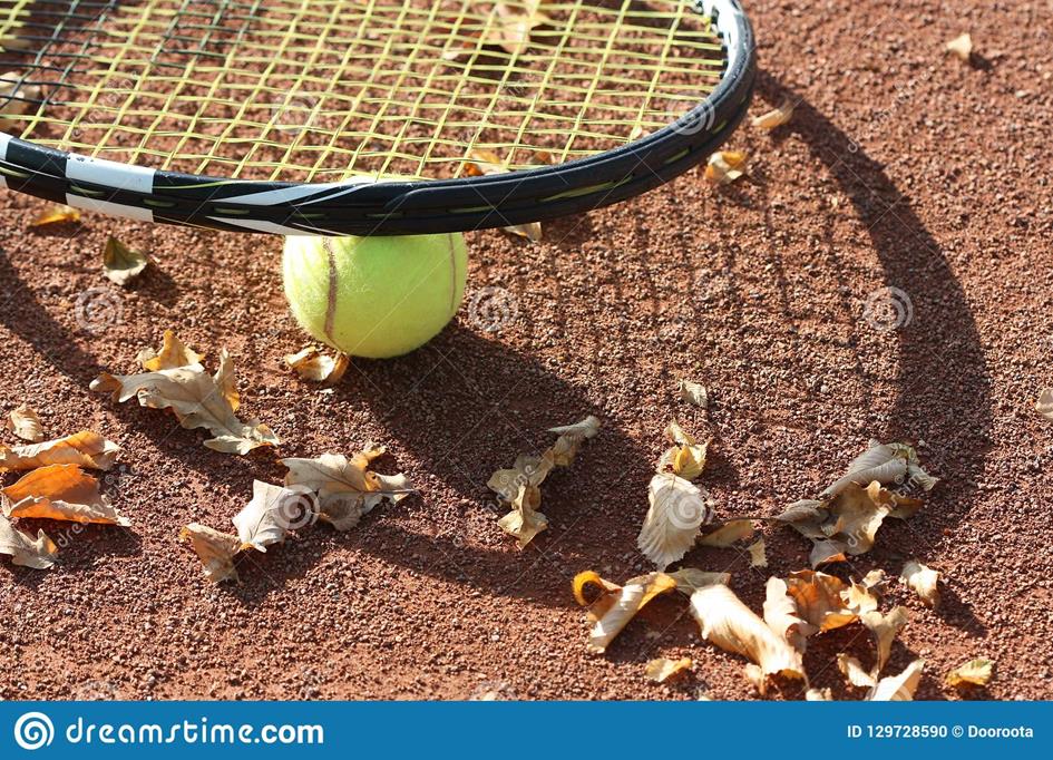 tennisbal-op-de-hof-en-herfstbladeren-129728590.jpg